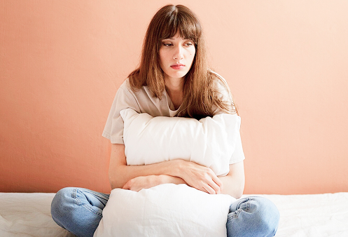 Uma mulher sentada, olhando fixamente para o vazio com uma expressão de desalento, transmitindo a luta interna com questões de autoestima.